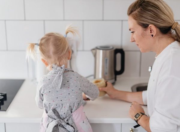 A mother helps her young daughter bake on a kitchen counter, creating a precious bonding moment.