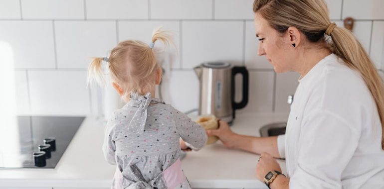 A mother helps her young daughter bake on a kitchen counter, creating a precious bonding moment.