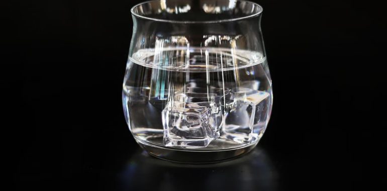 A refreshing glass of ice water placed against a dark backdrop, highlighting clarity and simplicity.