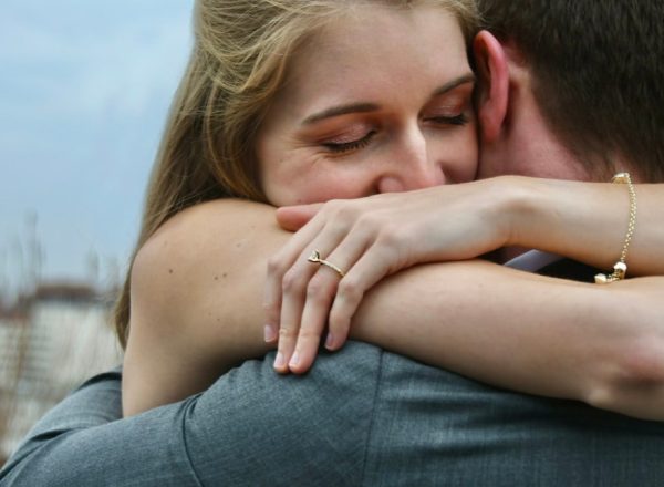 man in blue denim jeans kissing woman in white shirt